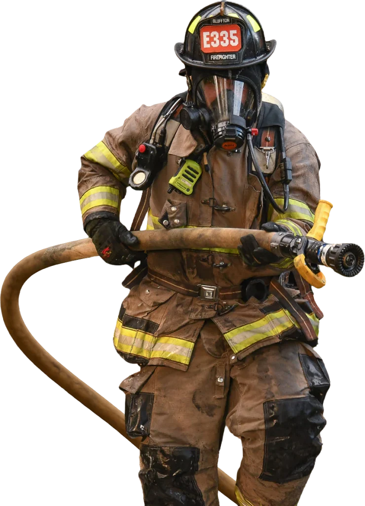 A firefighter in full protective gear and helmet holds a fire hose, ready for action. The uniform is tan with yellow reflective stripes, and the person is wearing a face mask and breathing apparatus.