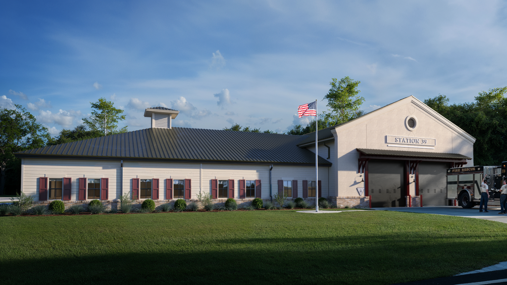A modern, single-story fire station with beige siding, red shutters, and a metal roof. An American flag flies out front, and a fire truck is partially visible at the garage entrance labeled "Station 50.